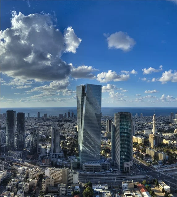 מבט אווירי על תל אביב עם מגדלי משרדים ים ושמיים מעוננים
