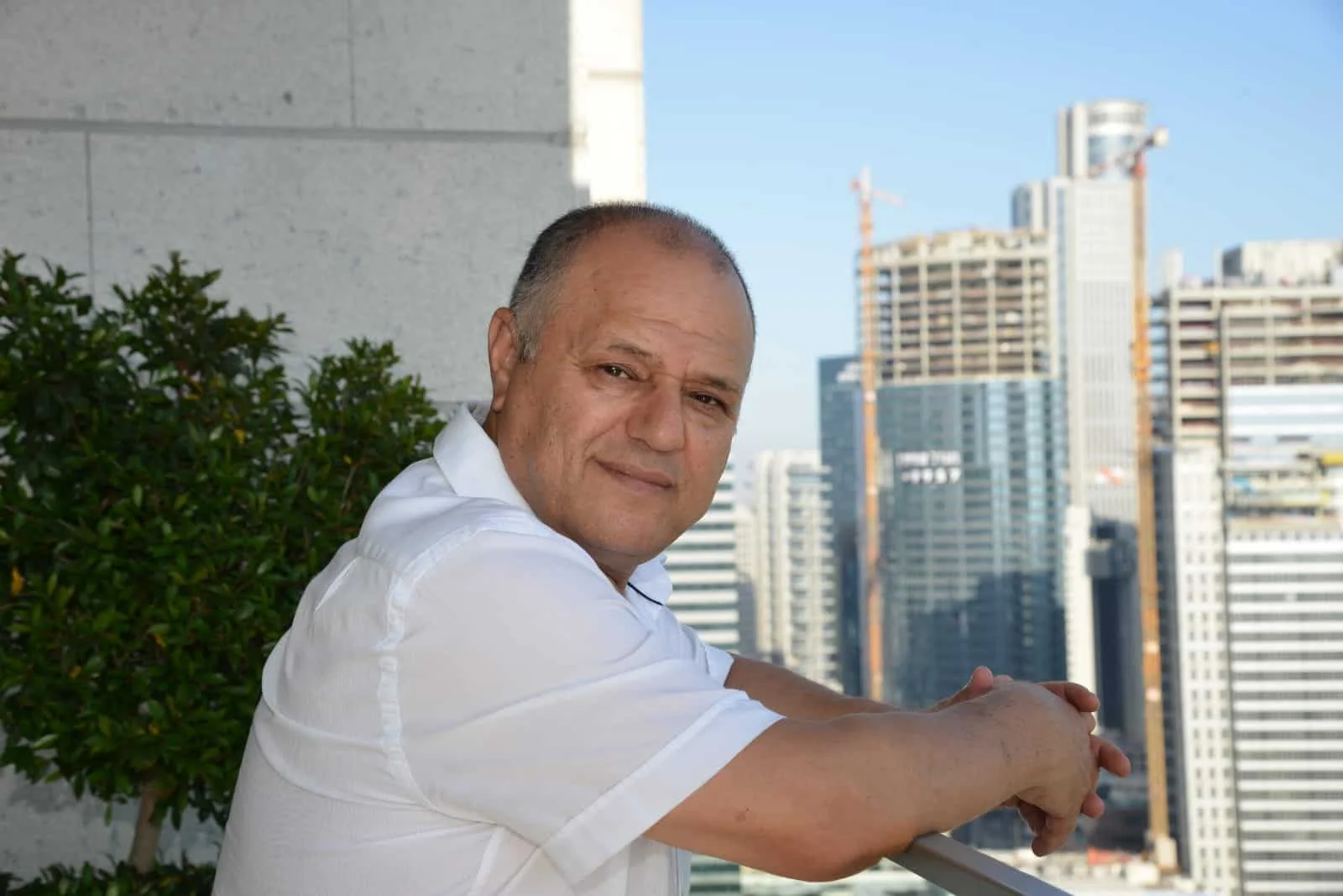 גבר בחולצה לבנה משקיף מהמרפסת אל נוף מגדלי עסקים